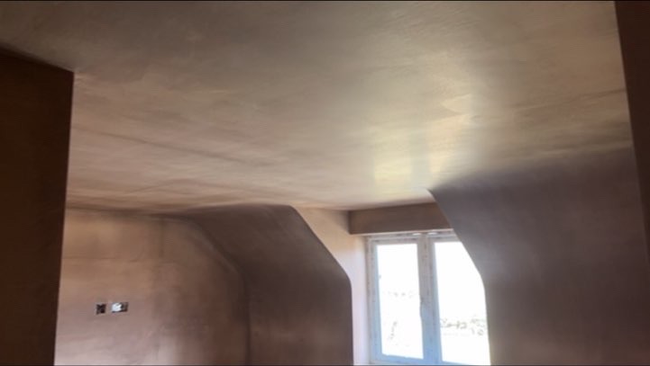 Smooth plaster finish on a sloped ceiling beside a window