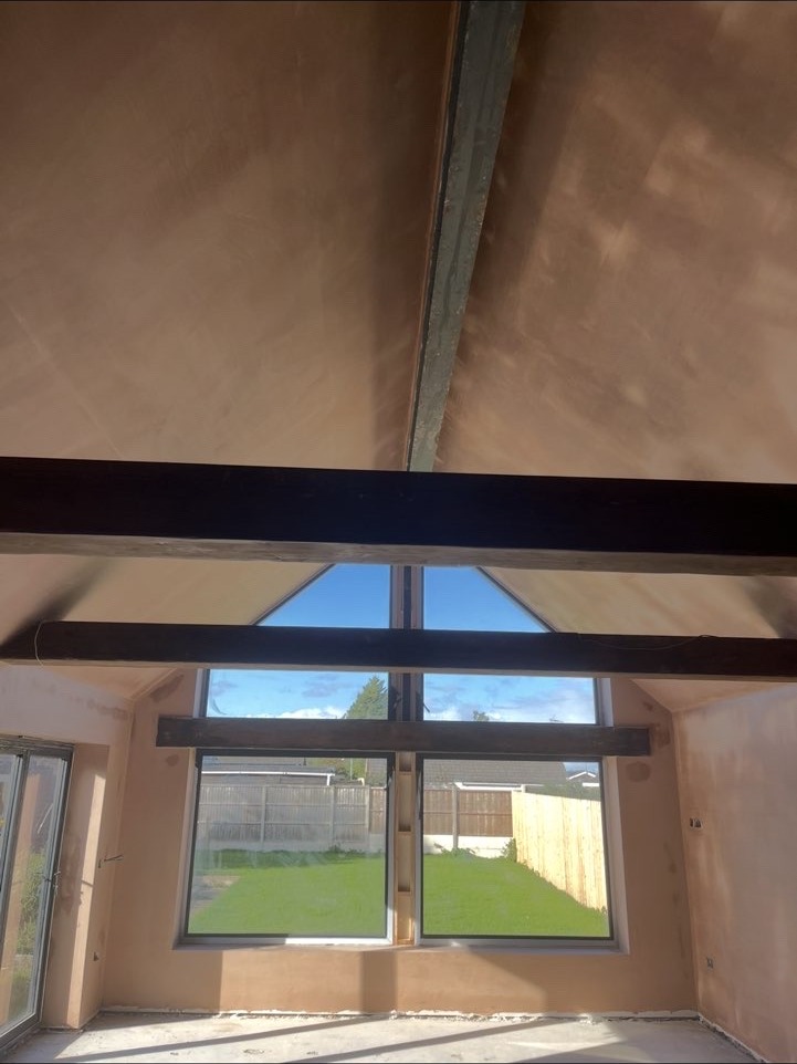 Plastered vaulted ceiling with exposed beams and an apex window