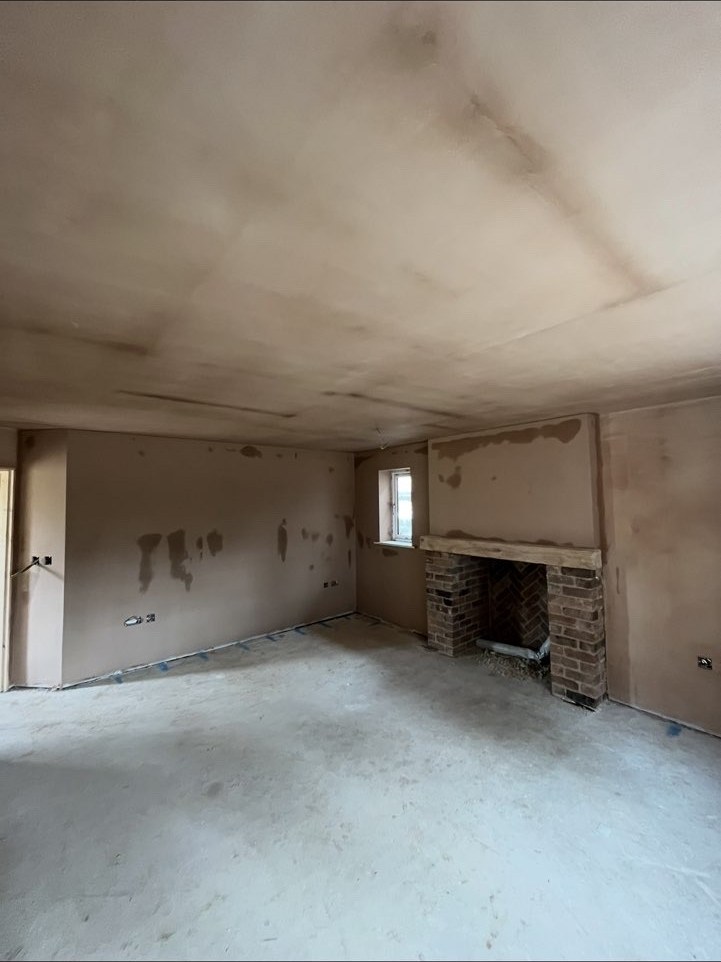 Plastered open-plan room with a brick fireplace